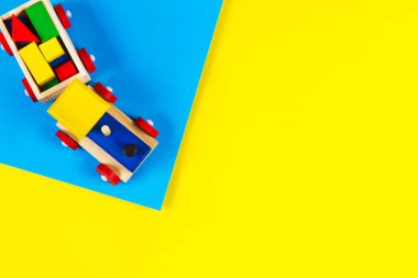 Açık mavi ve sarı arka planda renkli blokları olan tahta oyuncak tren. Üst görünüm