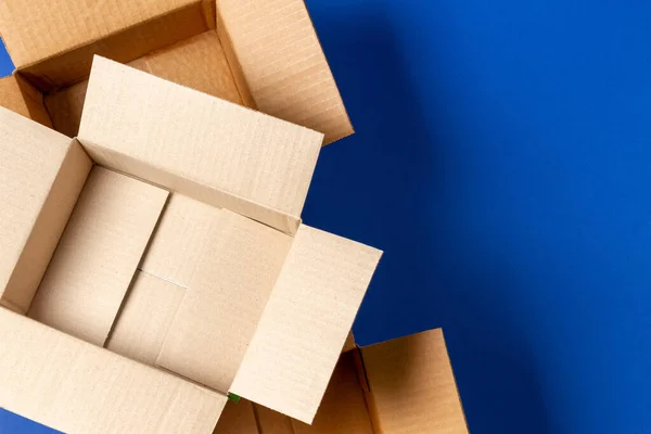 Empty open cardboard boxes on blue background. Top view — Stock Photo, Image