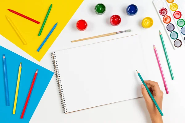 아이들이 손으로 색칠 된 연필을 가지고 미술 도구들이 있는 스케치북 위에 그림을 그립니다. 학습, 취미, 예술적 배경. 위에서 본 풍경 — 스톡 사진