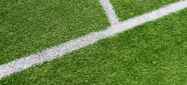 Yeşil yapay çim futbol sahası arka planında beyaz çizgiler var. Üst görünüm