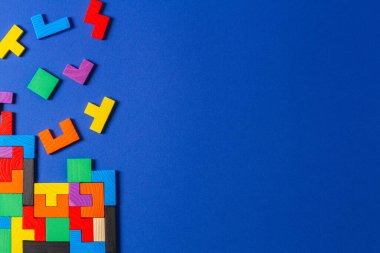 Farklı renkte şekiller mavi arka planda ahşap bulmaca blokları. Geometrik şekiller farklı renklerde, üst görünüm, boşluk kopyala