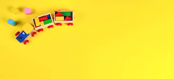 Wooden toy train with colorful blocks on yellow background. Top view — Stock Photo, Image