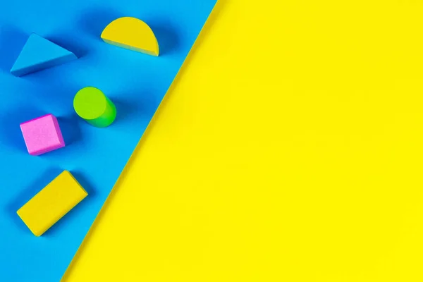 Дерев'яні барвисті блоки на геометричному жовтому і синьому фоні. Вид зверху, плоский ліжко — стокове фото
