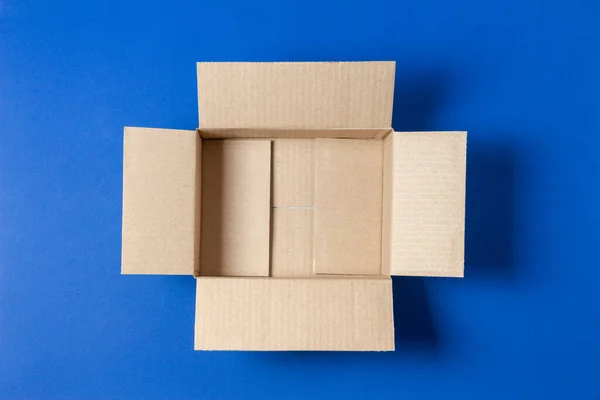 Uma caixa de papelão marrom aberta vazia no fundo azul. Vista superior — Fotografia de Stock