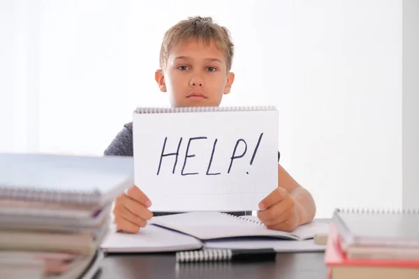 Dificuldades de aprendizagem, escola, conceito de educação em quarentena. Cansado menino decepcionado sentado à mesa com muitos livros. Ajuda do Word escrito no notebook — Fotografia de Stock