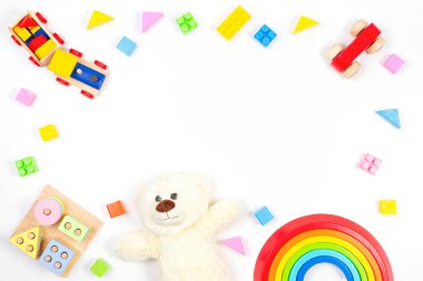 Oyuncak bebek çerçevesi beyaz arka planda oyuncak ayı ve renkli tahta oyuncaklarla. Üst manzara, düz uzanma