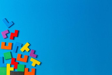 Farklı renkli şekiller, açık mavi arkaplanda tahta yapboz blokları. Geometrik şekiller farklı renklerde, üst görünüm, boşluk kopyala