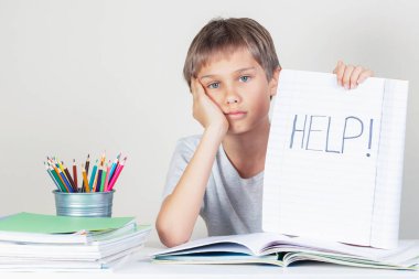 Ödev yapan üzgün çocuk ve defteri kelime ile tutuyor Yardım
