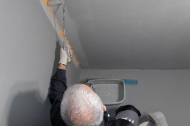 Banyo duvarına ve yere su geçirmez boya uygulayan bir inşaat işçisi. Banyoya su yalıtımı uyguluyorum..