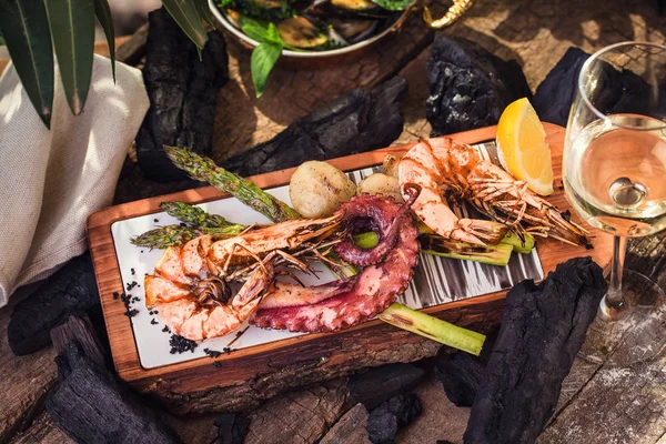 Dish of seafood on a wooden board with a glass of wine — Stock Photo, Image