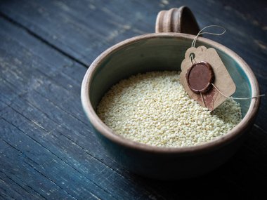 Mavi ahşap arka planda bir kasede beyaz susam tohumları