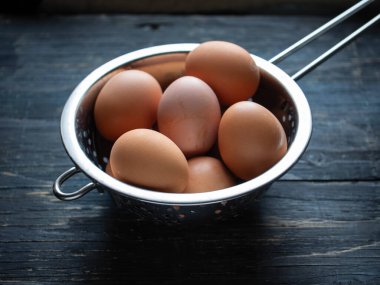 Mavi ahşap arka planda süzgeçte tavuk yumurtası