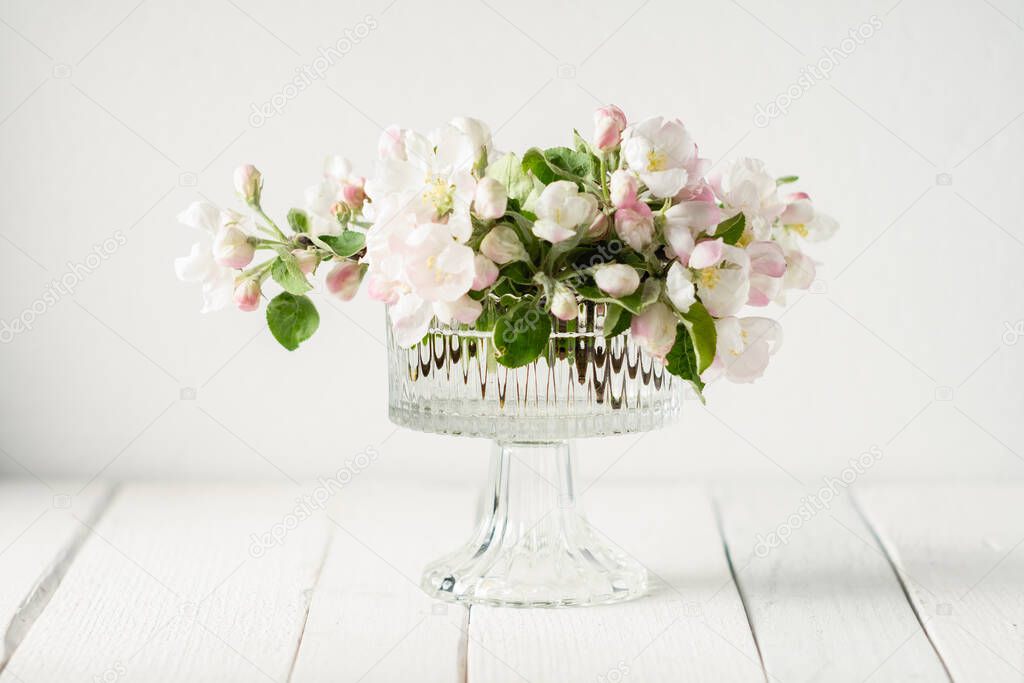 flowering branch of apple in a vase on a white wooden background