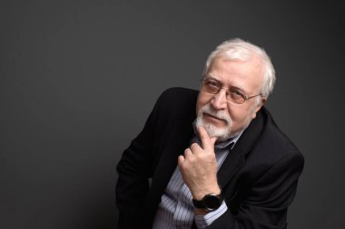 İş adamı, gri saçlı, gözlüklü, gri saçlı adam ciddi görünüyor.