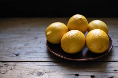 Koyu bir masada sarı kokulu limonlar