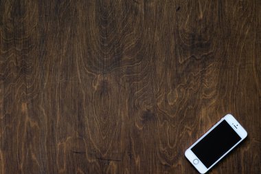 Telefon ahşap bir dokuda, üst görüntüde metin için boşluk var.