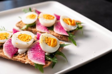 Turp ve roka ile haşlanmış yumurtalı tahıllı renkli sandviçler.