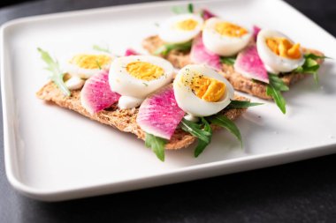 Turp ve roka ile haşlanmış yumurtalı tahıllı renkli sandviçler.