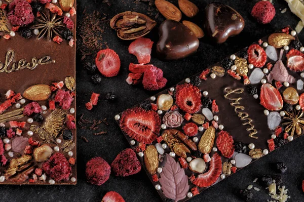 黑巧克力和牛奶巧克力 带有手工制作的冻干浆果和坚果 黑色背景下自然 上视图 — 图库照片