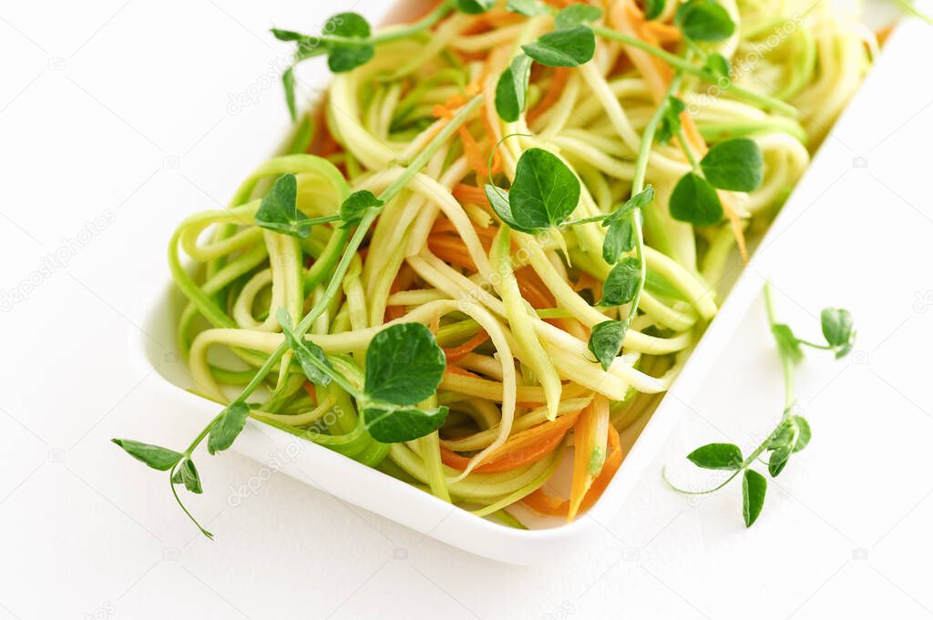 close-up of a bright dish of young zucchini in the form of a paste with microgreen peas on a white background
