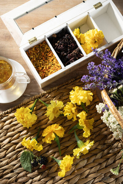 Colorful flowers and herbal tea arranged on a wooden table with a woven placemat