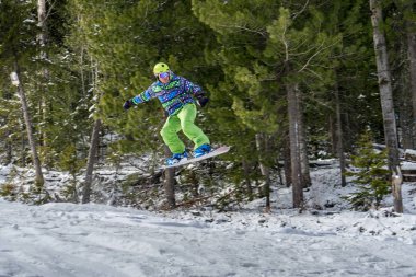 Dağlarda bir orman arka plan üzerinde atlama snowboarder