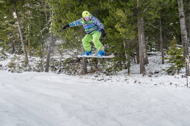 Dağlarda bir orman arka plan üzerinde atlama snowboarder
