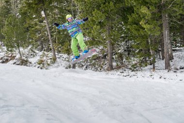 Dağlarda bir orman arka plan üzerinde atlama snowboarder