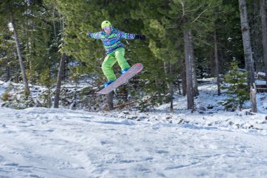 Dağlarda bir orman arka plan üzerinde atlama snowboarder