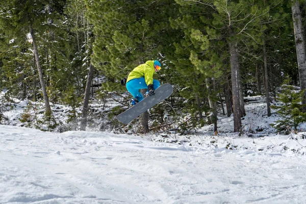 Snowboarder springen in de bergen op de achtergrond van een bos — Stockfoto