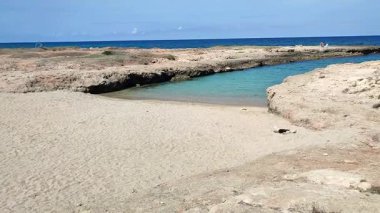 Ostuni, Puglia, İtalya 17 Eylül 2025: Kosta Merlata 'nın engebeli kayalıkları boyunca uzanan küçük altın kumsal