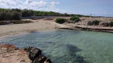 Ostuni, Puglia, İtalya 17 Eylül 2025: Kosta Merlata 'nın engebeli kayalıkları boyunca uzanan küçük altın kumsal