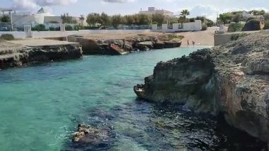 Ostuni, Puglia, İtalya 17 Eylül 2025: Kosta Merlata 'nın engebeli kayalıkları boyunca uzanan küçük altın kumsal