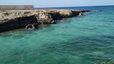 Ostuni, Puglia, İtalya 17 Eylül 2025: Kosta Merlata 'nın engebeli kayalıkları boyunca uzanan küçük altın kumsal