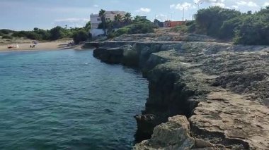 Ostuni, Puglia, İtalya 17 Eylül 2025: Kosta Merlata 'nın engebeli kayalıkları boyunca uzanan küçük altın kumsal