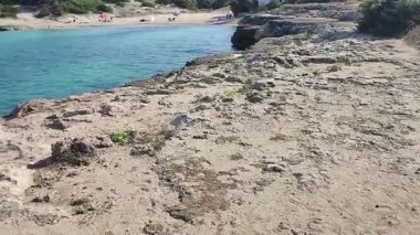 Ostuni, Puglia, İtalya 17 Eylül 2025: Kosta Merlata 'nın engebeli kayalıkları boyunca uzanan küçük altın kumsal