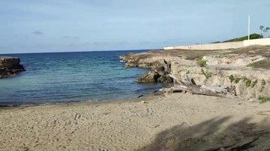 Ostuni, Puglia, İtalya 17 Eylül 2025: Kosta Merlata 'nın engebeli kayalıkları boyunca uzanan küçük altın kumsal