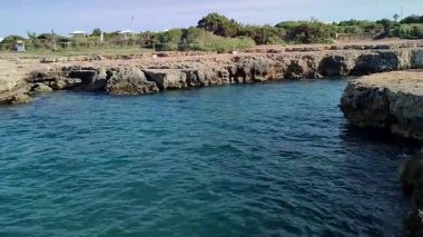 Ostuni, Puglia, İtalya 17 Eylül 2025: Kosta Merlata 'nın engebeli kayalıkları boyunca uzanan küçük altın kumsal