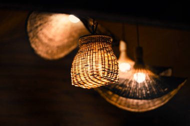 Zarif bir şekilde örülmüş lamba zarif bir şekilde aydınlatılarak sıcak bir ortam yaratıyor.