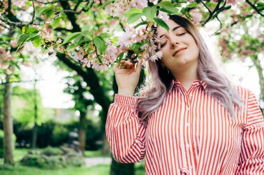 Park güneşli günde kiraz çiçeği mevsiminde zevk güzel genç kadın