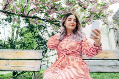 Park güneşli günde kiraz çiçeği mevsiminde zevk güzel genç kadın