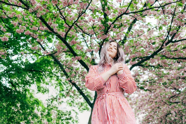 Park güneşli günde kiraz çiçeği mevsiminde zevk güzel genç kadın