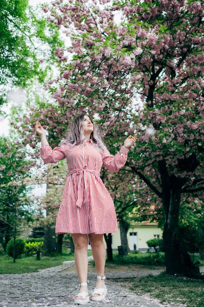 Bahçede yürüyüş kırmızı şeritli elbiseli Genç kadın