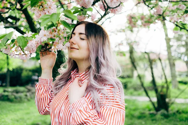 Park güneşli günde kiraz çiçeği mevsiminde zevk güzel genç kadın