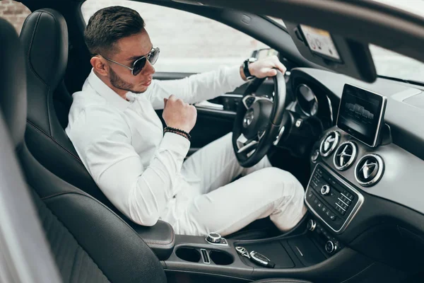 Lüks aracın içinde oturan yakışıklı genç adam