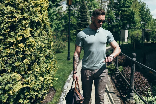 Sakallı ve güneş ışığı altında sokakta şık kıyafet poz içinde gözlüklü genç adam