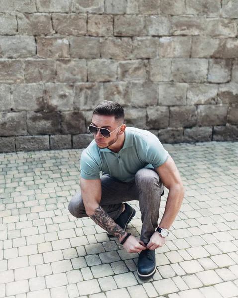 Sakallı ve güneş ışığı altında sokakta şık kıyafet poz içinde gözlüklü genç adam