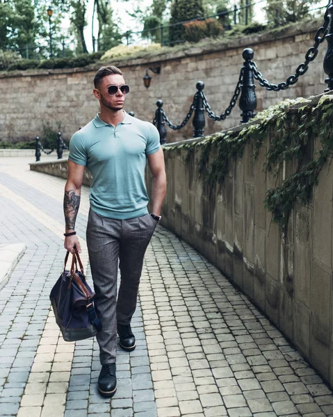 Sakallı ve güneş ışığı altında sokakta şık kıyafet poz içinde gözlüklü genç adam