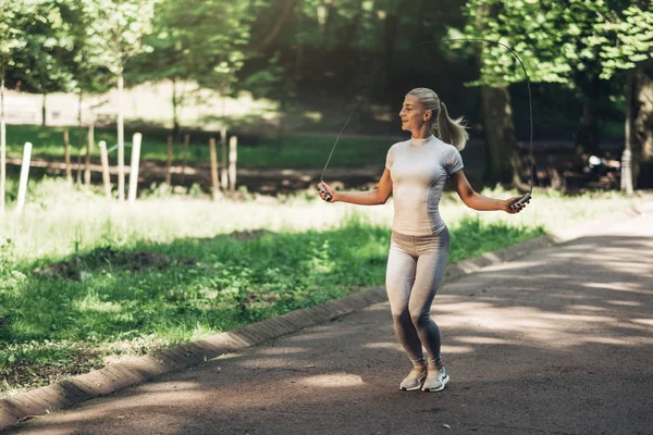 Park ip atlama ile uygun genç kadın portresi. Fitness erkek güneşli günde Park açık havada egzersiz yapıyor.