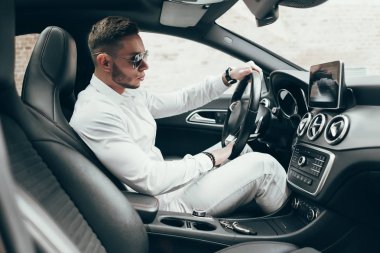 Lüks aracın içinde oturan yakışıklı genç adam